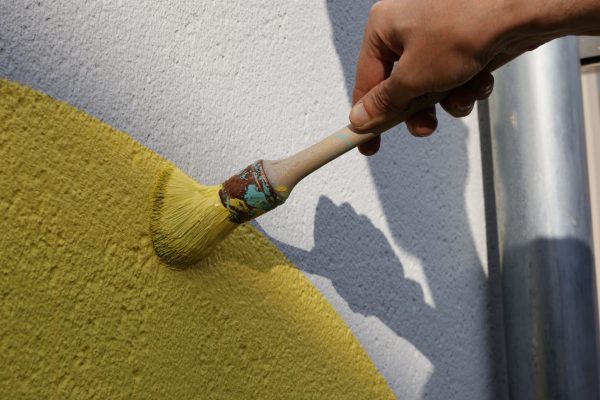 pinceau peignant un mur en jaune